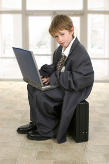 boy in a man's suit typing on a computer