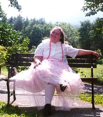 Louisa, a woman with Down syndrome, smiling broadly in a beautiful pink, gauzy dress.